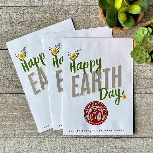 Three white seed packets that say "Happy Earth Day," with flowers blooming from the H and Y.