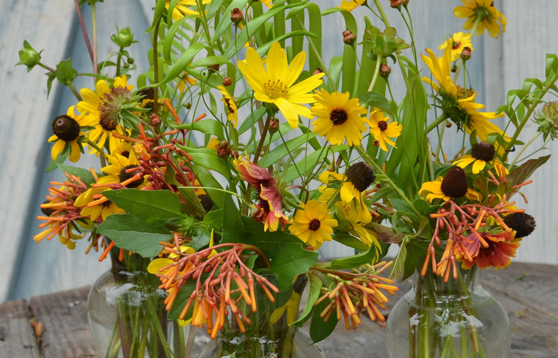 A bouquet of yellow and orange wildflowers with some greenery