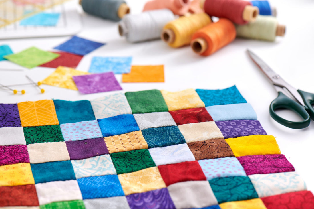 a picture of a quilt with multicolored tiny squares. Thread and scissors are in the background.