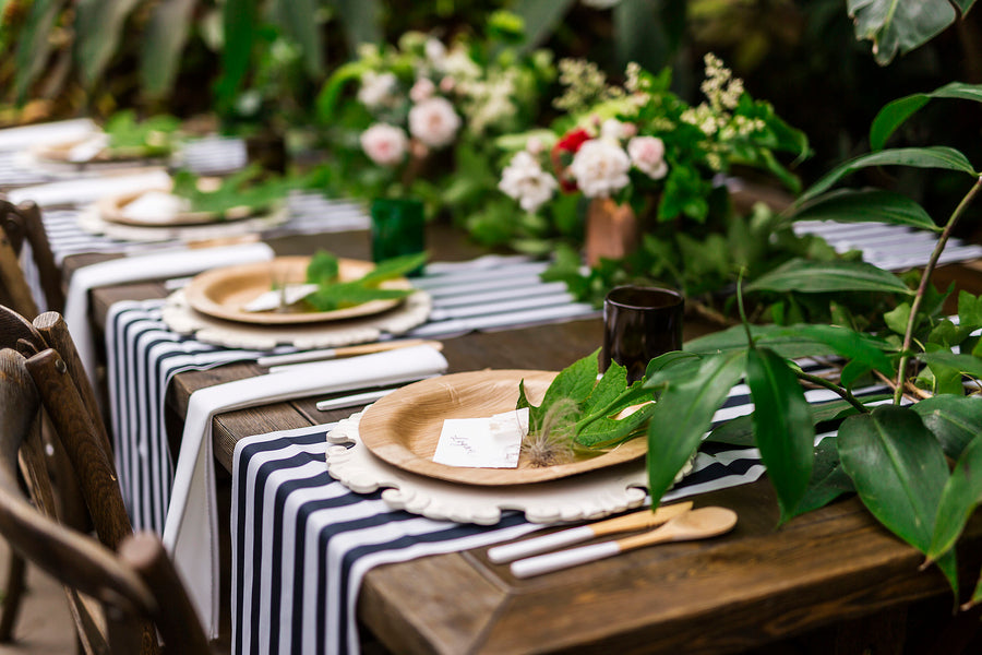 A wedding banquet table set with lovely greenery and earth friendly plates and utensils.