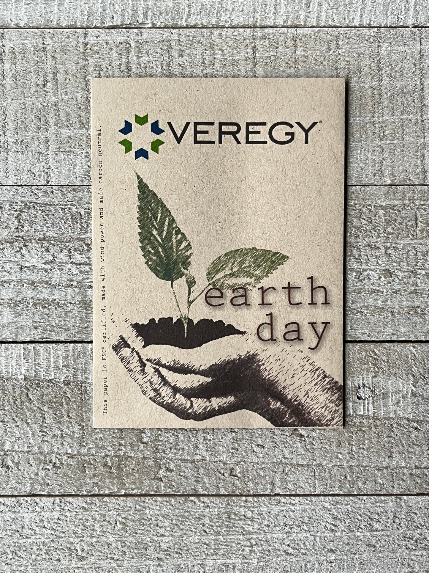 A brown seed packet with hands holding soil and a green sprout. A company logo is printed on top.