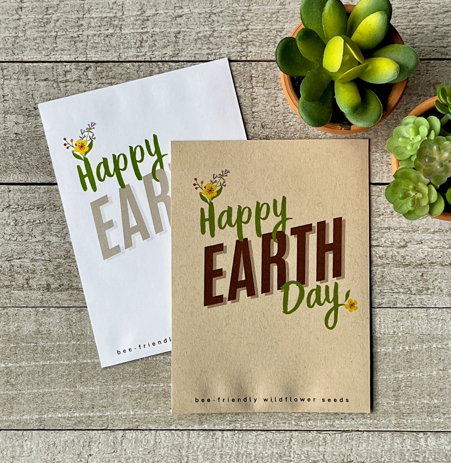 A white and a brown seed packet that say "Happy Earth Day," with flowers blooming from the H and Y.